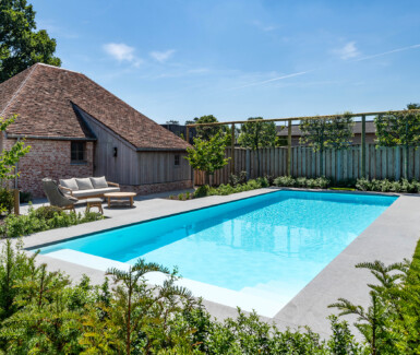 wit polypropyleen zwembad aangelegd door aquapura naast landelijke poolhouse
